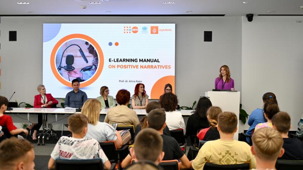 The image depicts a professional seminar with an audience of adults and children listening to a speaker at a podium, presenting 