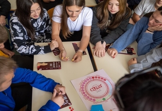 A group of children gathered around and playing the educational board game “Ciklus” 