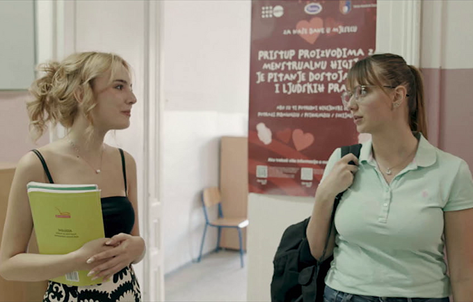 Two girls talking in a school setting