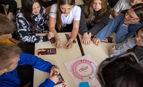 A group of children gathered around and playing the educational board game “Ciklus” 