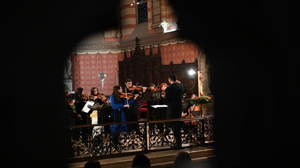 A small ensemble of musicians is performing inside a richly decorated venue that appears to be a historical churc